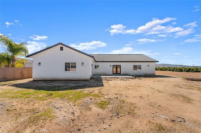 rear view of property with a tiled roof, a patio area, fence, and stucco siding