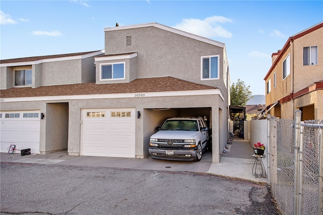 view of property featuring stucco siding, a shingled roof, and fence