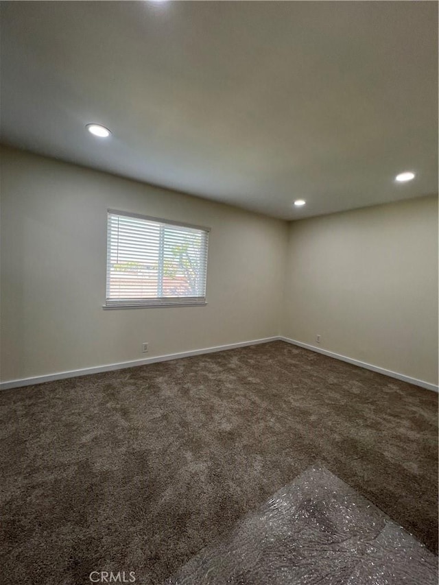 unfurnished room with baseboards, dark carpet, and recessed lighting