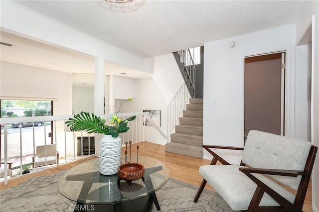 sitting room with a textured ceiling, light wood finished floors, and visible vents