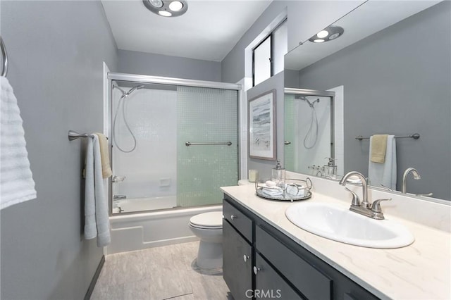 full bath with bath / shower combo with glass door, vanity, and toilet