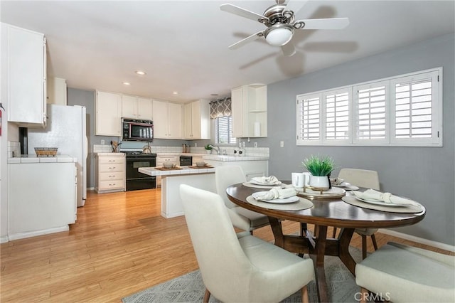 kitchen with black stove, light countertops, light wood-style floors, white cabinetry, and recessed lighting