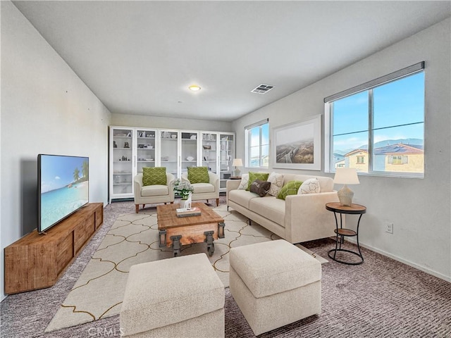 living area featuring baseboards, visible vents, and light colored carpet