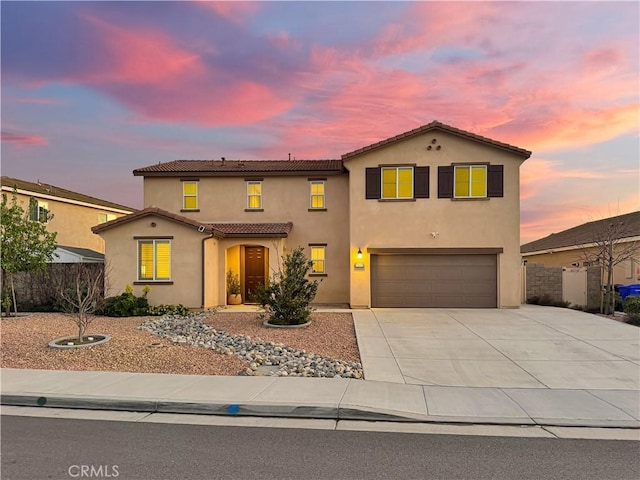 mediterranean / spanish home with stucco siding, concrete driveway, fence, a garage, and a tiled roof