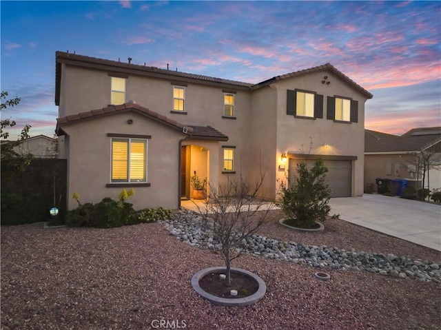 mediterranean / spanish-style house featuring concrete driveway, an attached garage, a tile roof, and stucco siding