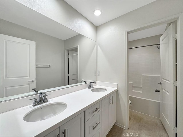 bathroom featuring a sink, bathing tub / shower combination, toilet, and double vanity