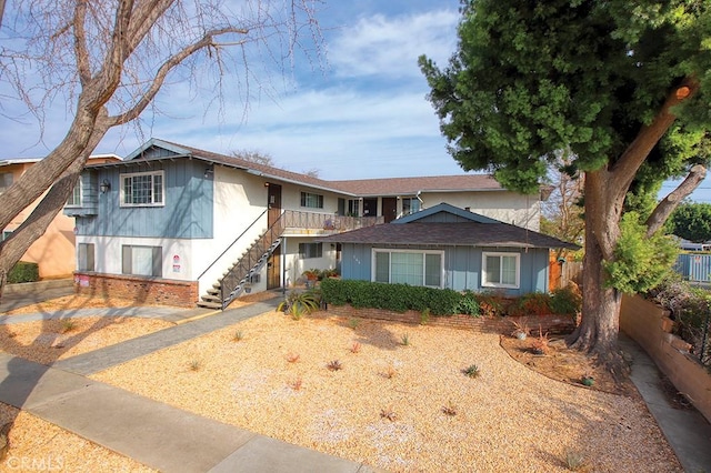 view of front of house featuring stairs, fence, and brick siding