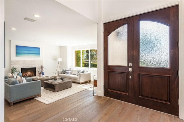 entryway with recessed lighting, visible vents, a lit fireplace, and light wood finished floors