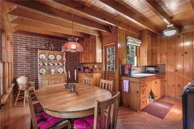 dining space with brick wall, wood walls, wood ceiling, light floors, and beamed ceiling