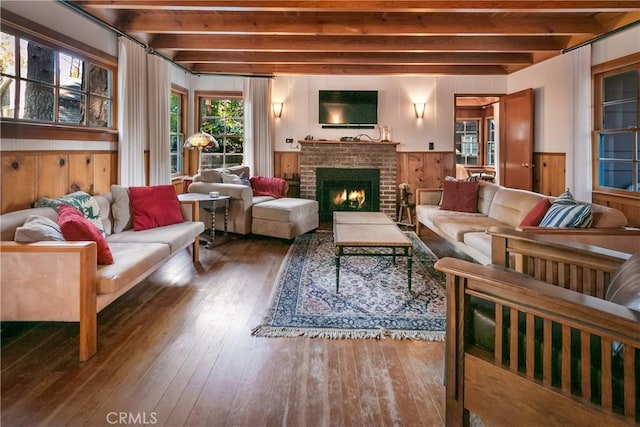 interior space featuring a wainscoted wall, wood walls, a fireplace, wood finished floors, and beam ceiling