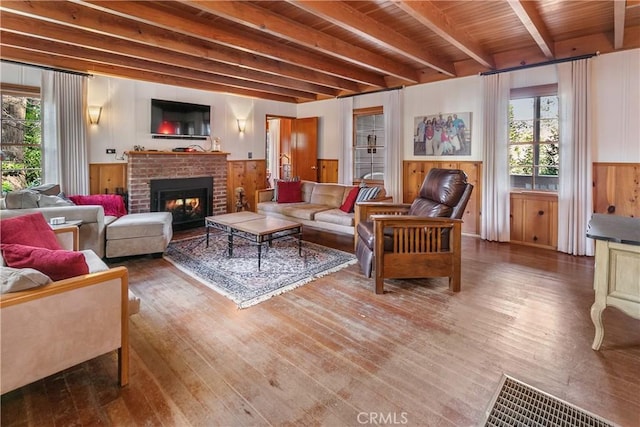 living room with beamed ceiling, plenty of natural light, wood finished floors, and visible vents