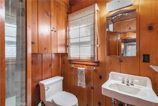 half bath with a sink, toilet, and wooden walls