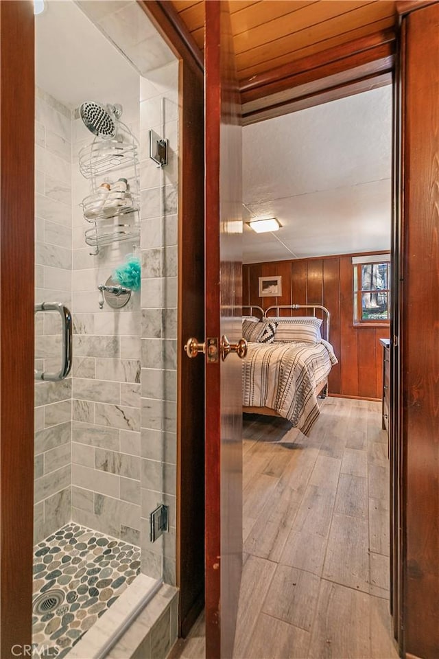 full bathroom featuring wood walls, a stall shower, wood finished floors, and visible vents