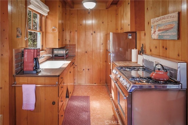 kitchen with light floors, wood walls, gas range oven, and a sink