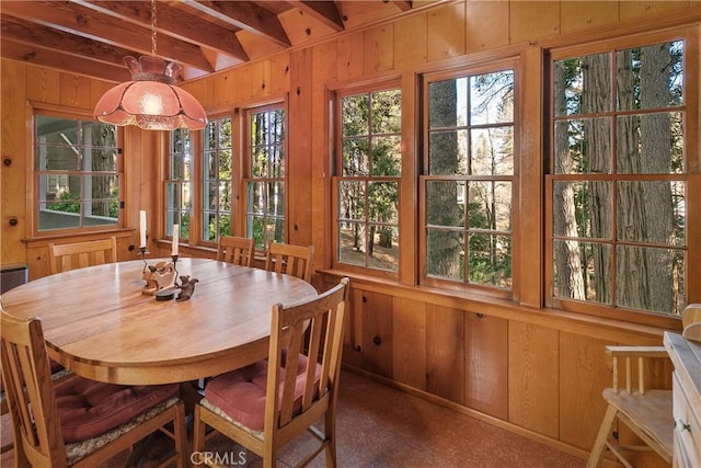 dining area featuring wood walls and beam ceiling