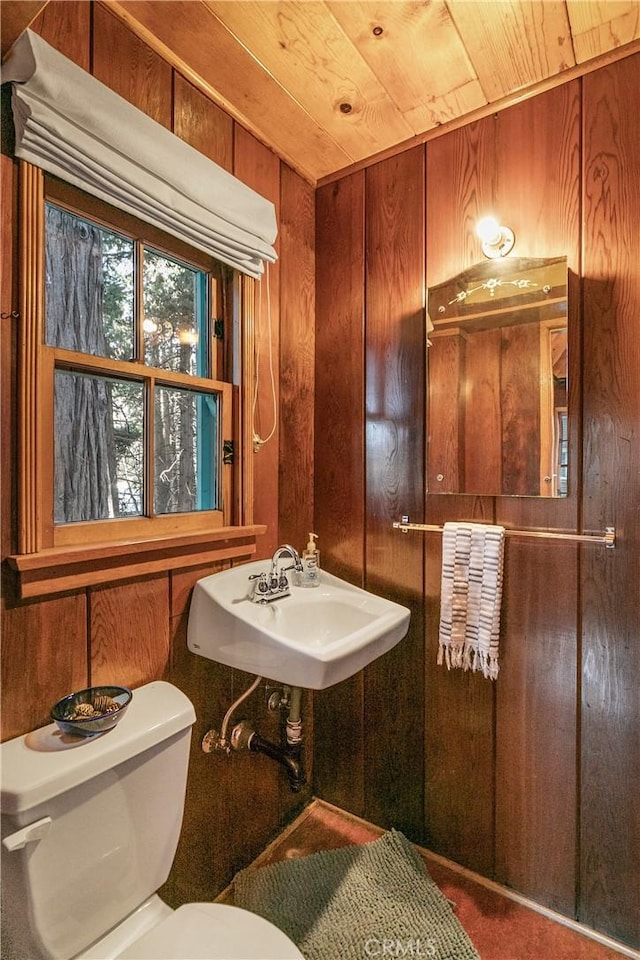 bathroom with wood ceiling, a sink, wooden walls, and toilet