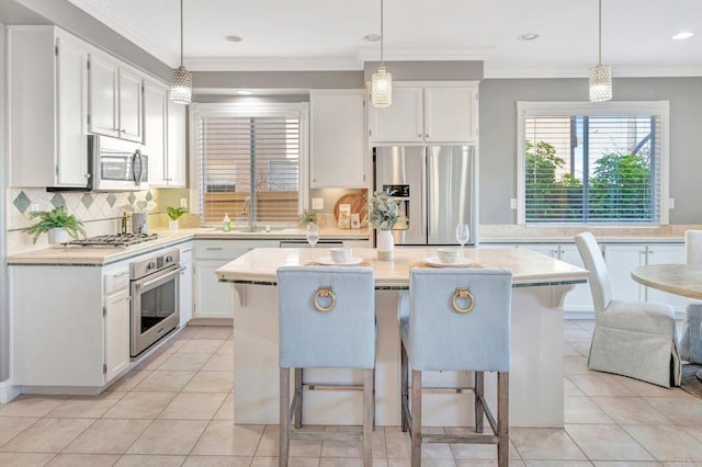 kitchen with pendant lighting, appliances with stainless steel finishes, white cabinetry, and a center island