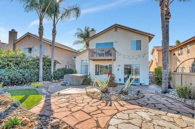 back of property featuring a patio area, a hot tub, fence, and a balcony