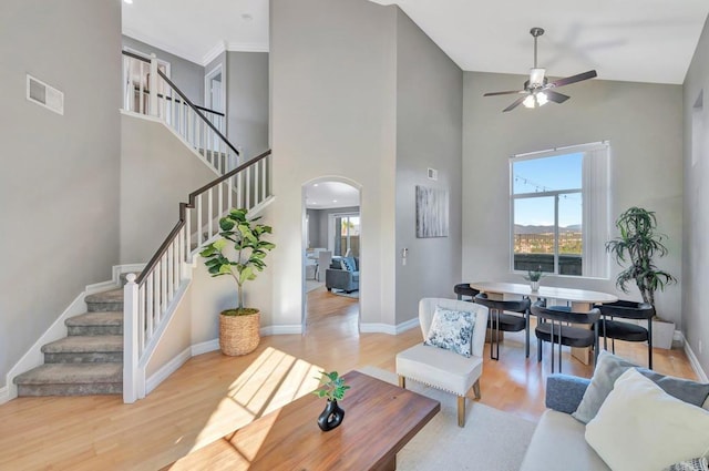 living area featuring arched walkways, visible vents, stairway, light wood-style flooring, and baseboards