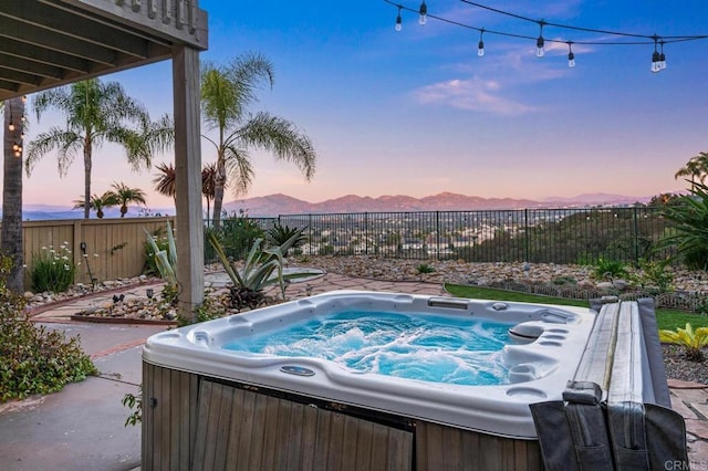 view of pool featuring a hot tub, a mountain view, and a fenced backyard