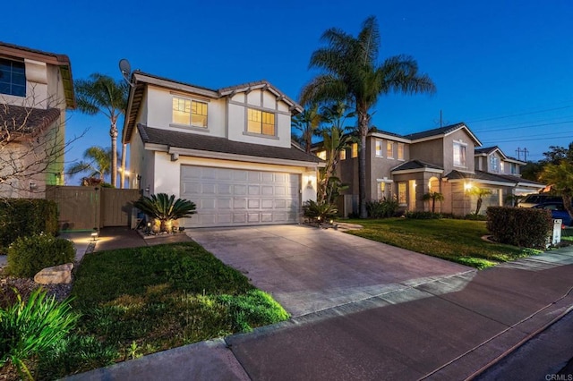 traditional-style house with stucco siding, an attached garage, fence, driveway, and a front lawn