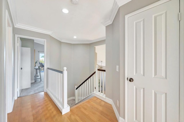 corridor featuring baseboards, wood finished floors, an upstairs landing, and crown molding