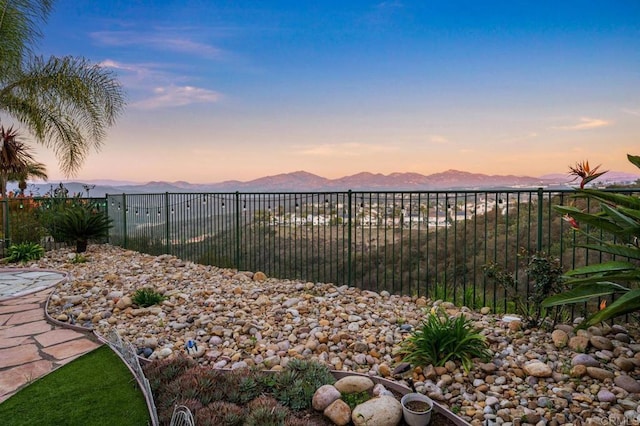 yard at dusk with fence and a mountain view