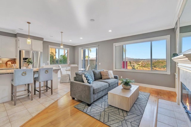 living room featuring baseboards, a fireplace, ornamental molding, and recessed lighting