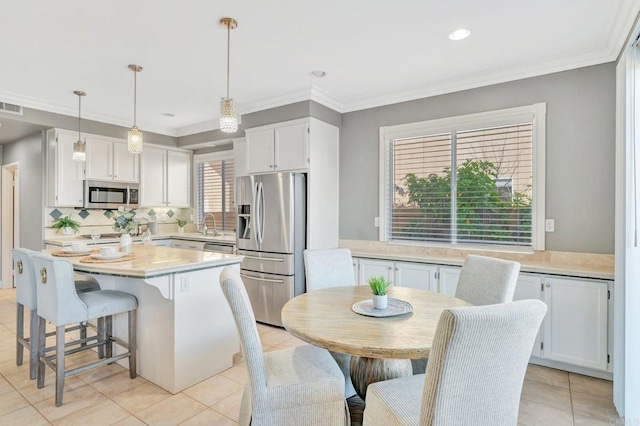 kitchen with white cabinets, stainless steel appliances, light countertops, and hanging light fixtures