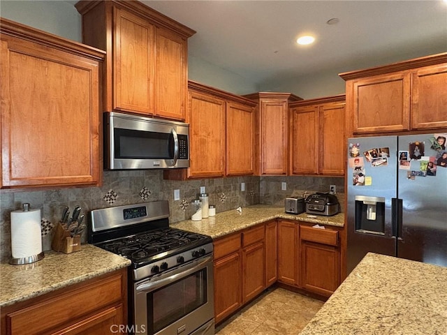 kitchen featuring light stone counters, brown cabinets, stainless steel appliances, recessed lighting, and tasteful backsplash