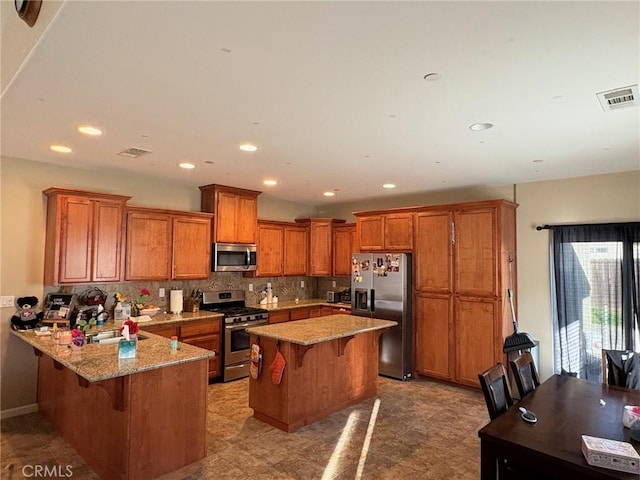 kitchen with stainless steel appliances, a peninsula, visible vents, and a kitchen breakfast bar