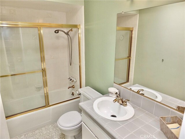 bathroom with enclosed tub / shower combo, vanity, and toilet