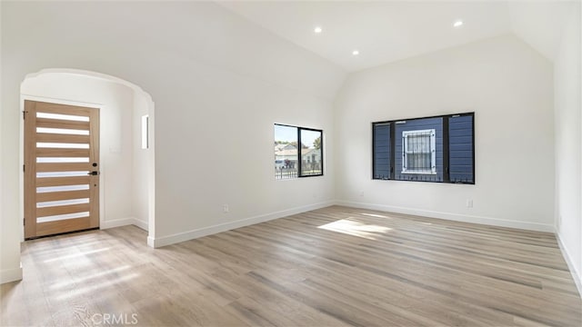 interior space with light wood-type flooring, baseboards, arched walkways, and recessed lighting