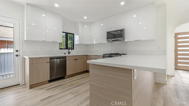 kitchen featuring stainless steel appliances, modern cabinets, a peninsula, and white cabinetry