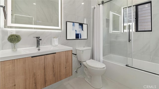 bathroom featuring tile walls, shower / bath combination with glass door, vanity, and toilet