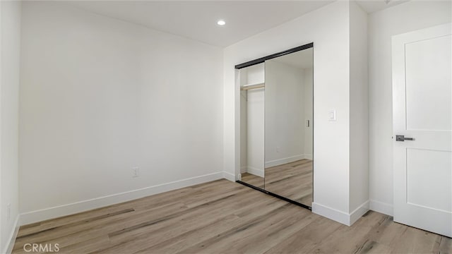 unfurnished bedroom featuring light wood-style flooring, baseboards, a closet, and recessed lighting