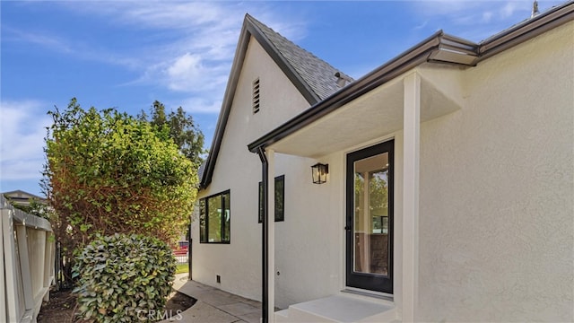 doorway to property featuring fence and stucco siding