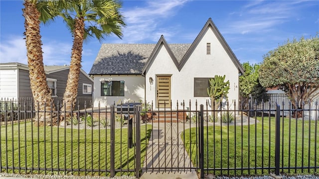 tudor home with a fenced front yard, roof with shingles, stucco siding, a front yard, and a gate