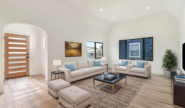 living area with arched walkways, recessed lighting, high vaulted ceiling, light wood-type flooring, and baseboards