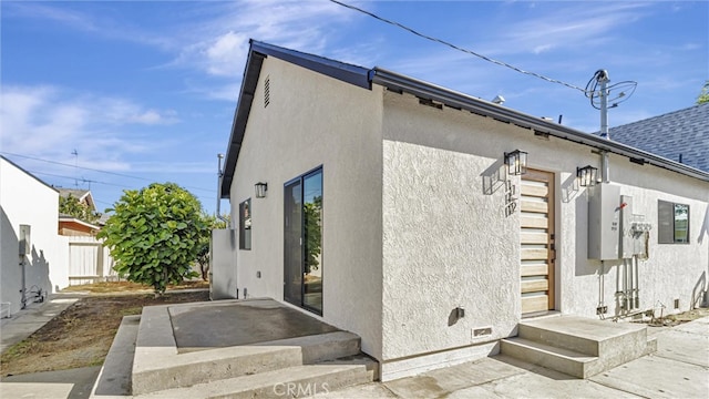 rear view of house with a patio area, fence, and stucco siding