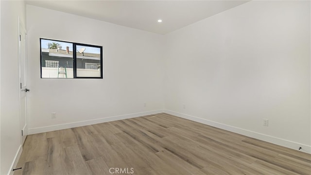 empty room featuring light wood finished floors, recessed lighting, and baseboards