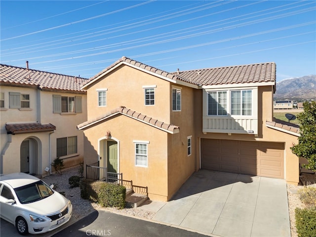 view of front of home featuring an attached garage, a tile roof, concrete driveway, stucco siding, and a mountain view