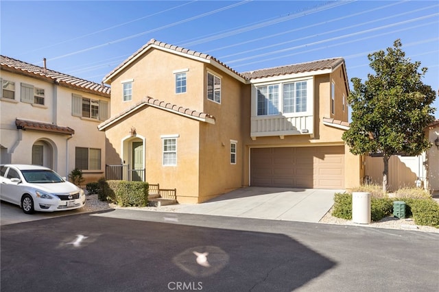 view of front of property featuring a tile roof, an attached garage, driveway, and stucco siding