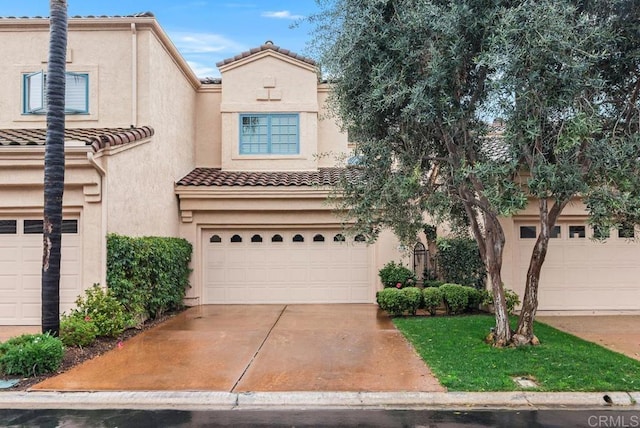 view of front of property with a garage, driveway, a tile roof, and stucco siding