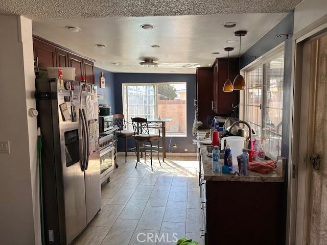 kitchen with hanging light fixtures, a textured ceiling, appliances with stainless steel finishes, and a sink