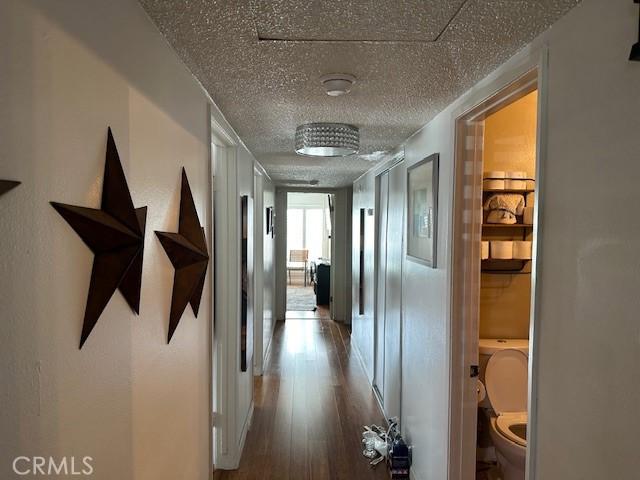 hall with a textured ceiling and wood finished floors