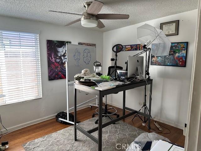 office area with a textured ceiling, wood finished floors, and baseboards