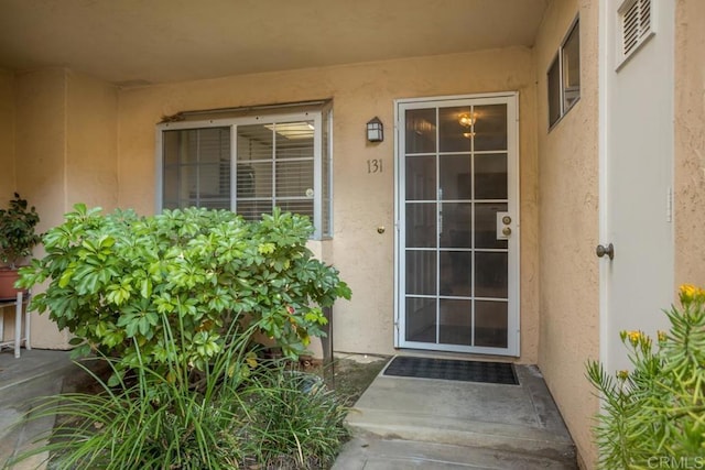 entrance to property with visible vents and stucco siding