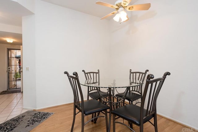 dining room featuring light wood-type flooring, baseboards, and a ceiling fan