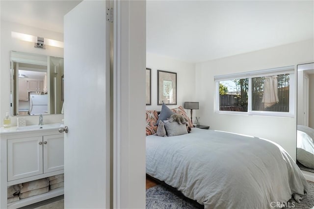 bedroom featuring ensuite bath, a sink, and freestanding refrigerator